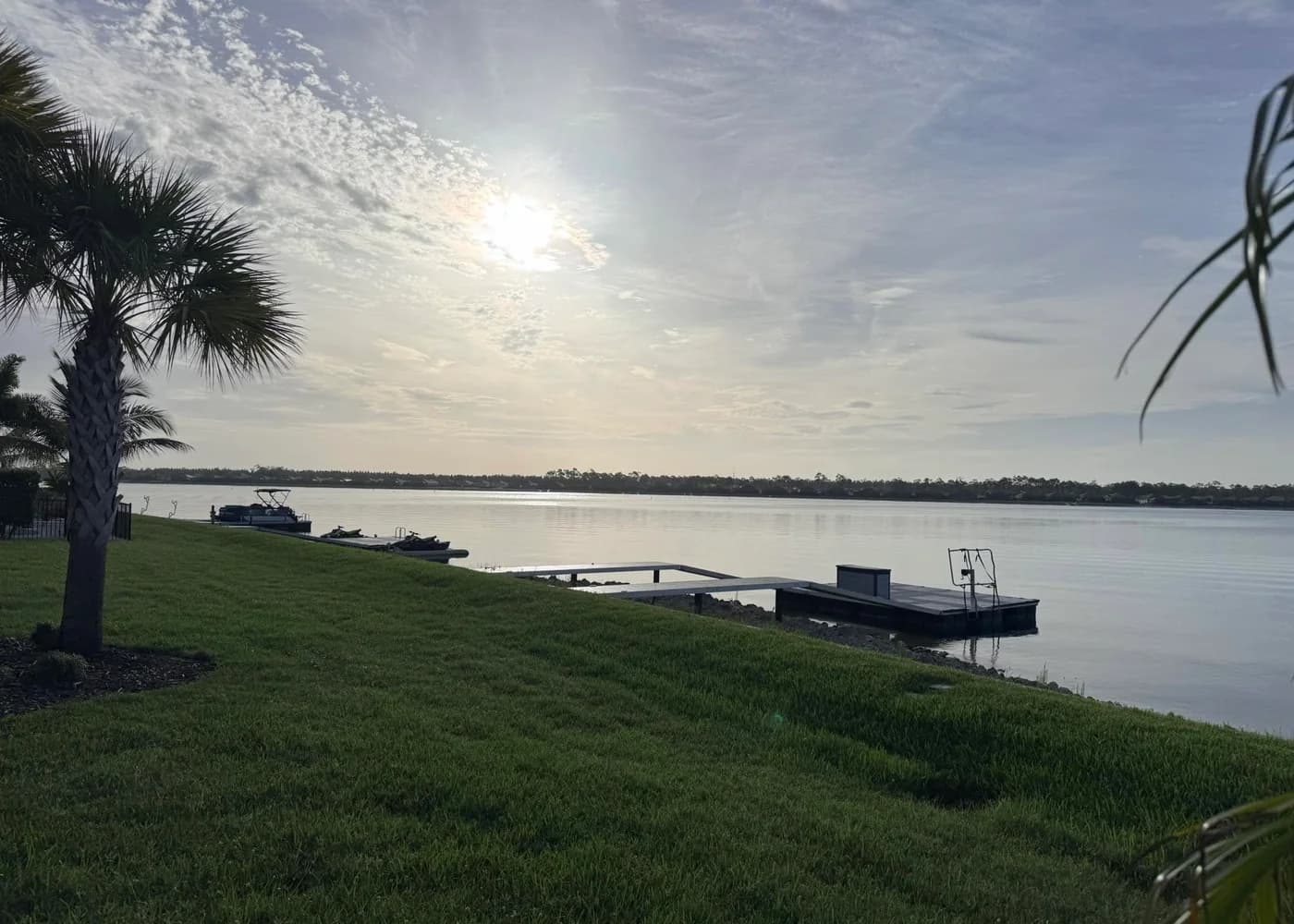 A calm WildBlue lake at sunrise with a boat, personal watercraft, and neighborhood docks